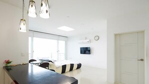 Une cuisine moderne dotée d’un long plan de travail, de luminaires suspendus et d’un coin repas avec un canapé et des chaises.