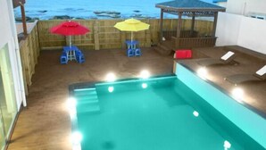 Un espace piscine avec vue sur l’océan, une terrasse en bois et un belvédère.