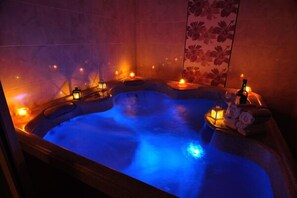 A hot tub with blue lighting, candles, and a bottle of champagne. - Pohang Sea Shore Pension (Pohang)