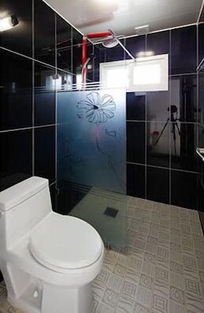 A bathroom with a white toilet, a shower area, and a glass partition with a floral design. - Pohang Sea Shore Pension (Pohang)