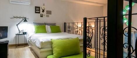 Un dormitorio con cama, mesita de noche, lámpara y ventana con detalles decorativos.