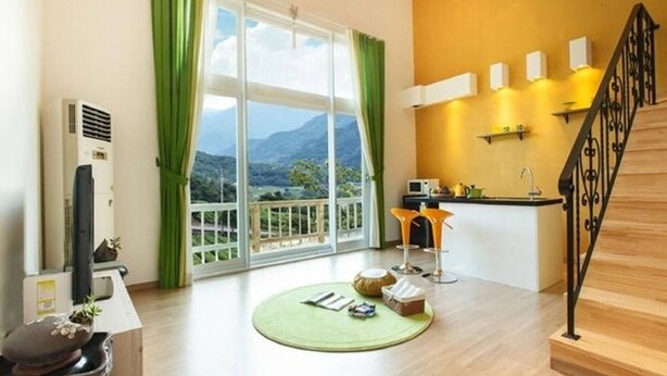 A modern living room with a large window, a kitchen area, and a staircase. - Emotion Pension (Hadong)