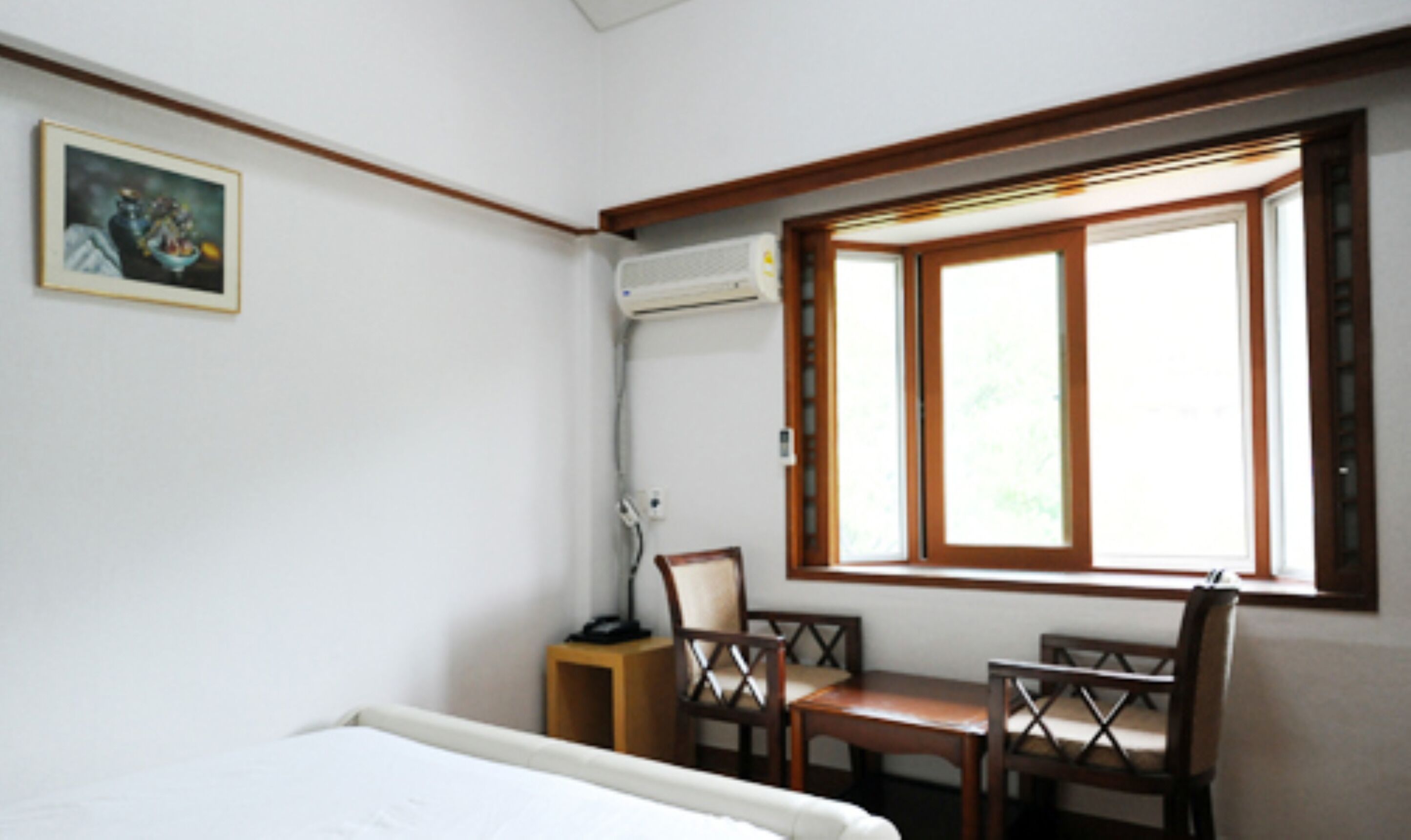 Una habitación de hotel con una cama, un escritorio, una silla y una ventana con persianas.