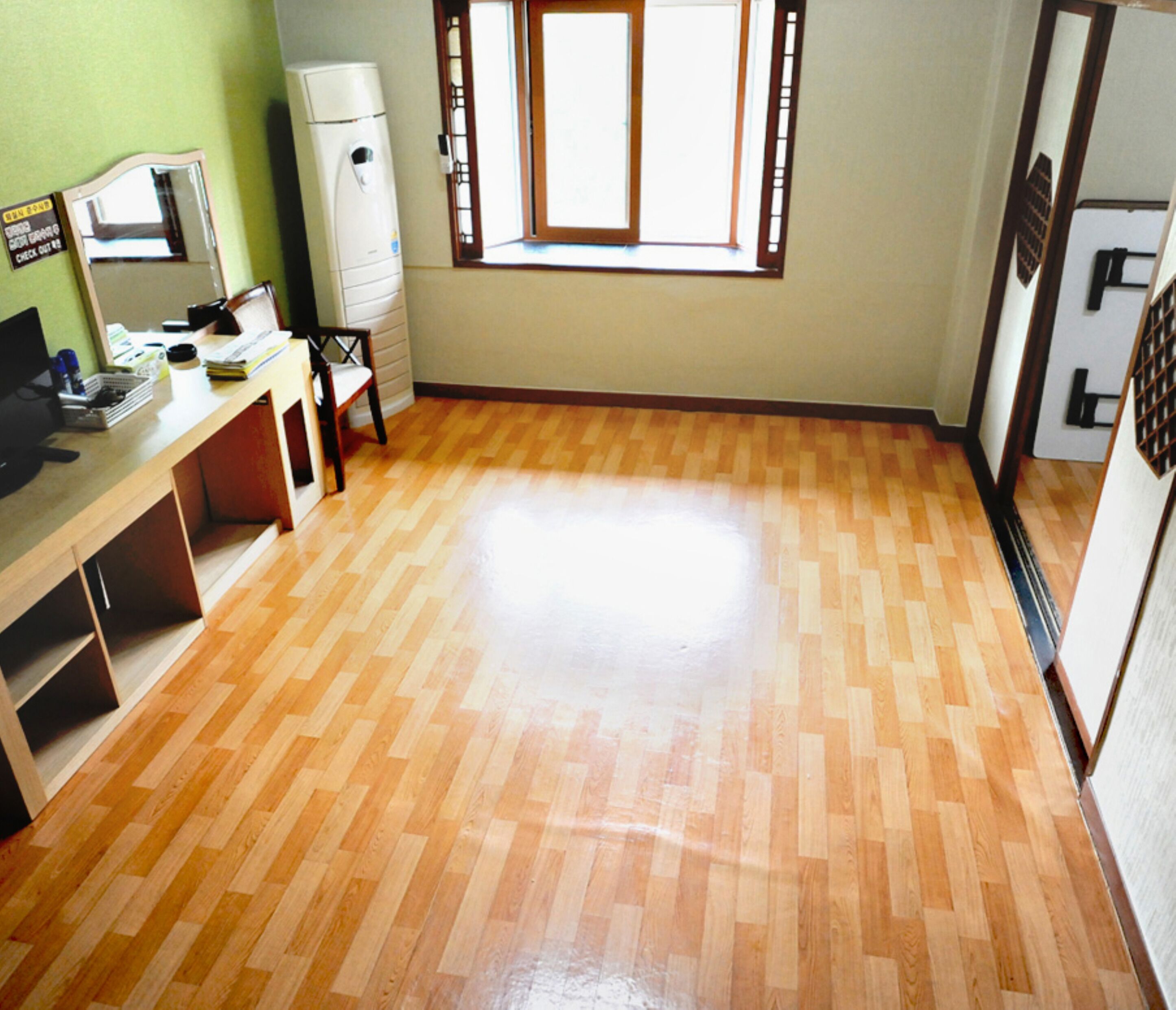 Una cocina con piso de madera, una ventana y un refrigerador.