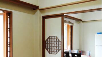 Una habitación con suelo de madera, una mesa de comedor con sillas y un refrigerador blanco.