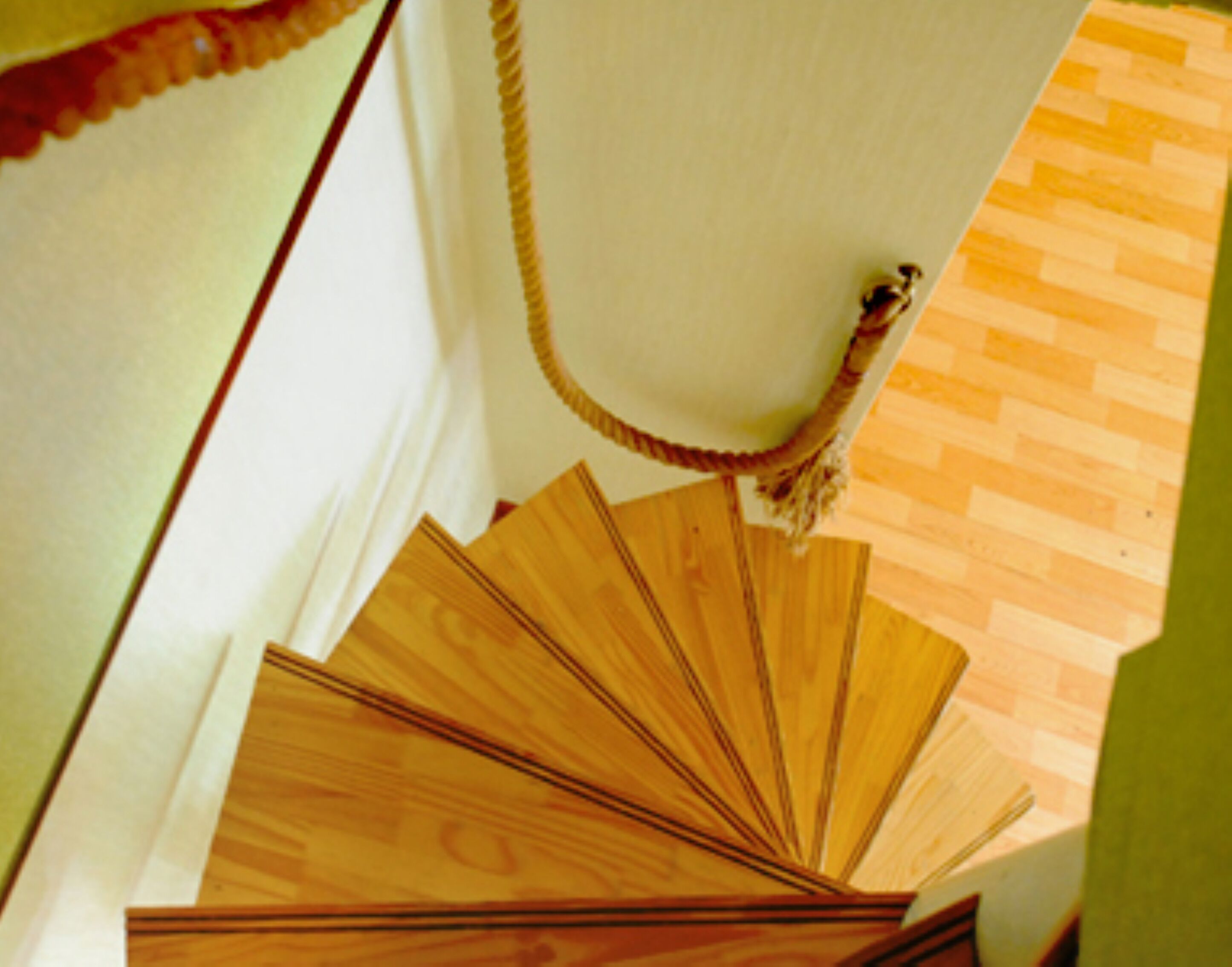 Una escalera de caracol con escalones de madera y barandilla de cuerda.