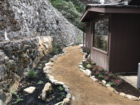 A pathway leading to a building with a stone wall on one side and a garden with rocks and plants on the other. - Vintage Adelaida Home on 16 acres (Paso Robles)