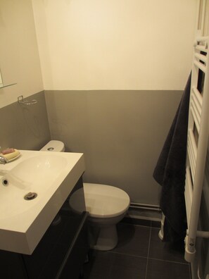 Une petite salle de bain avec un lavabo blanc, des toilettes et un porte-serviettes.
