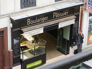 Une devanture de magasin avec une enseigne indiquant « Boulanger-Pâtissier » et une vitrine remplie de pains.