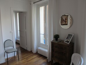 A room with a wooden floor, a radiator, a chair, a dresser, and a picture frame on the wall.