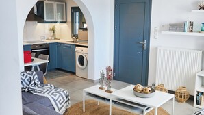 Una sala de estar moderna con un sofá gris, una mesa de centro blanca y una cocina visible a través de un arco.