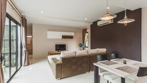 Een moderne woonkamer met een bank, eettafel en televisie.