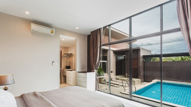 Een moderne hotelkamer met een groot bed, een badkamer met douche en uitzicht op een buitenzwembad.
