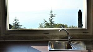 A kitchen with a stainless steel sink and a window overlooking a body of water and trees. - Beautiful apartment in Imperia Porto Maurizio, best panoramic area of the city (Imperia)