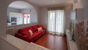 A modern living room with a red sofa, a marble bench, and a TV on a white stand. - Beautiful apartment in Imperia Porto Maurizio, best panoramic area of the city (Imperia)