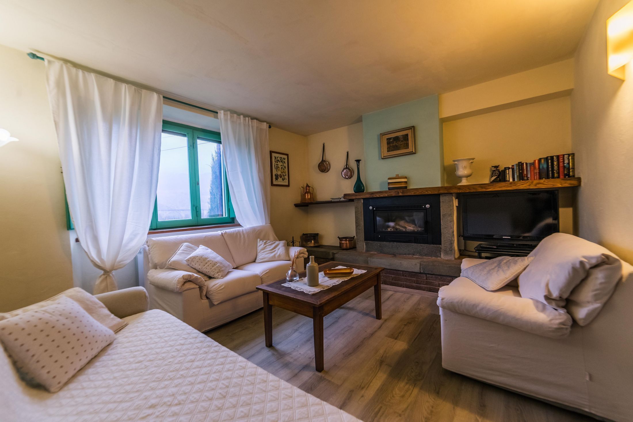 A cozy living room with a fireplace, a sofa, a coffee table, and a bookshelf.