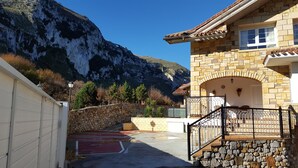 A stone building with a balcony and a mountain backdrop. - Exclusive apartment in beach Sonabia with a view to the sea and the mountain. (Castro Urdiales)