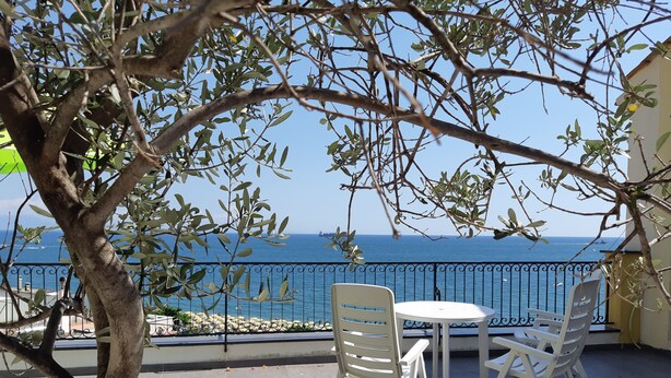 Una terraza con una mesa y sillas, con vista a una playa y el mar.
