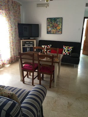 A living room with a dining table, chairs, a sofa, a television, and a painting on the wall. - GOLF,SUN AND BEACH IN  AMAZING APARTMENT IN COSTA  BALLENA-ROTA WITH WIFI&TV SAT (COSTA BALLENA ROTA)