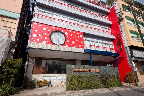 Ein Gebäude mit roter und weißer Fassade, einem großen Fenster und einem Schild mit japanischen Schriftzeichen.