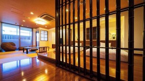 A traditional Japanese-style room with tatami flooring, a low wooden partition, and a bed with white bedding.