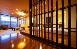 Ein traditionell japanisch gestalteter Raum mit Tatami-Böden, einem niedrigen Holzbett und einer Schiebetür mit vertikalen Bambuslatten.
