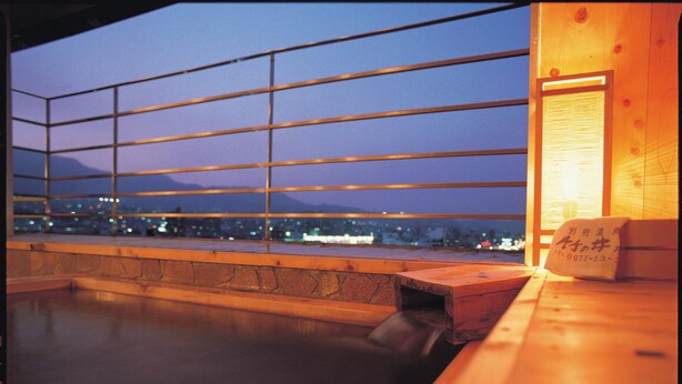 A wooden deck with a view of a cityscape and mountains at dusk.