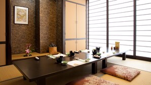 A traditional Japanese-style room with tatami flooring, a low table set for a meal, and sliding doors.