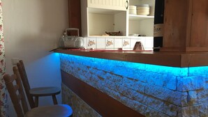 Una cocina con salpicadero de piedra, una silla de madera y un radio en la encimera.