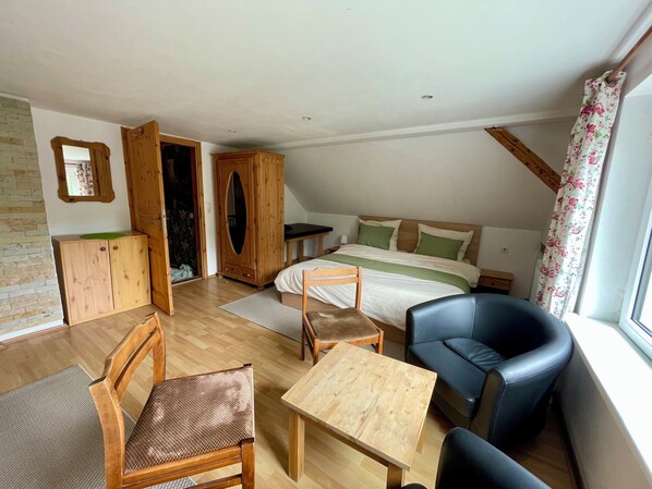 A bedroom with a bed, a desk, a chair, a wardrobe, and a window with curtains.
