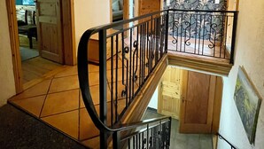 Una escalera de madera con barandilla negra que lleva a un balcón.