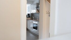 Una cocina moderna con armarios blancos, horno empotrado y campana extractora de acero inoxidable.