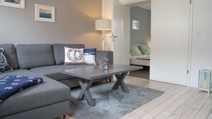 Una sala de estar moderna con un sofá seccional gris, una mesita y una lámpara.