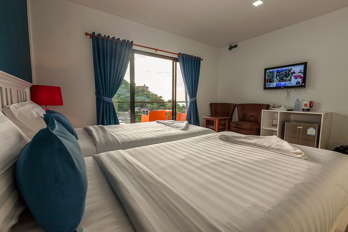 A hotel room with two beds, a television, a desk, and a chair.