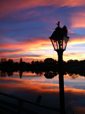 A sunset over a calm lake with a silhouette of a lamp post in the foreground. - GREAT LOCATION WATERFRONT, HEATED POOL! BEAUTIFUL SUNSETS, ALL PETS STAY FREE! (Holiday)