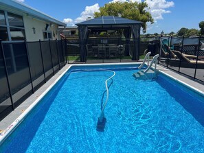 A rectangular swimming pool with clear blue water, surrounded by a black fence. - GREAT LOCATION WATERFRONT, HEATED POOL! BEAUTIFUL SUNSETS, ALL PETS STAY FREE! (Holiday)