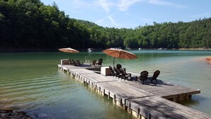 A wooden dock extending into a calm lake, with several chairs and two umbrellas. - Lakefront Adventure: Private Hot Tub,  Dock, Nearby Rafting, Biking & More! (Robbinsville)