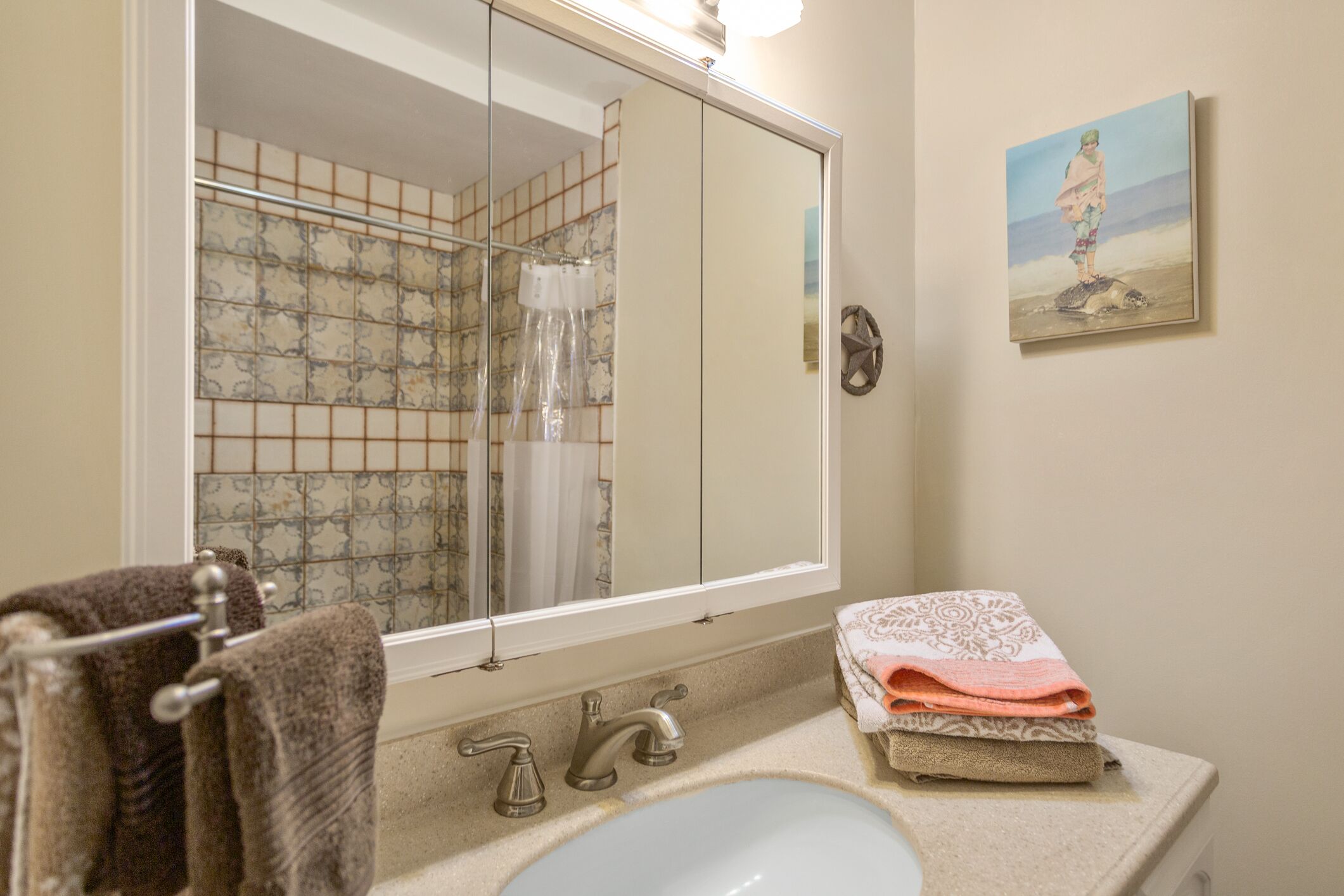 A bathroom with a large mirror, a sink, and a towel rack.