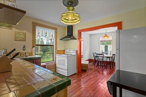 Kitchen features a central island with a tiled backsplash, a stove, and oven, leading to a dining area with a table and chairs.