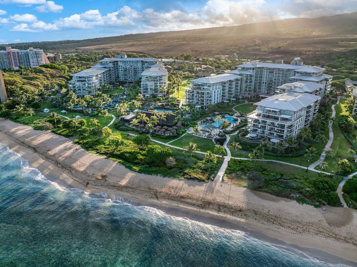 Ein Küstenresort mit mehreren Hochhäusern, einem Strandabschnitt und einem Poolbereich.