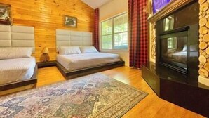 Una habitación con paredes de madera, una chimenea, dos camas y un tapete grande.