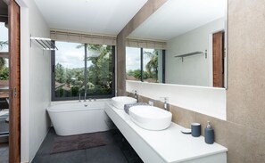 A modern bathroom with a large bathtub, two sinks, and a large window offering a view of greenery. - Picasso Villa Phuket - Pablo (Choeng Thale)