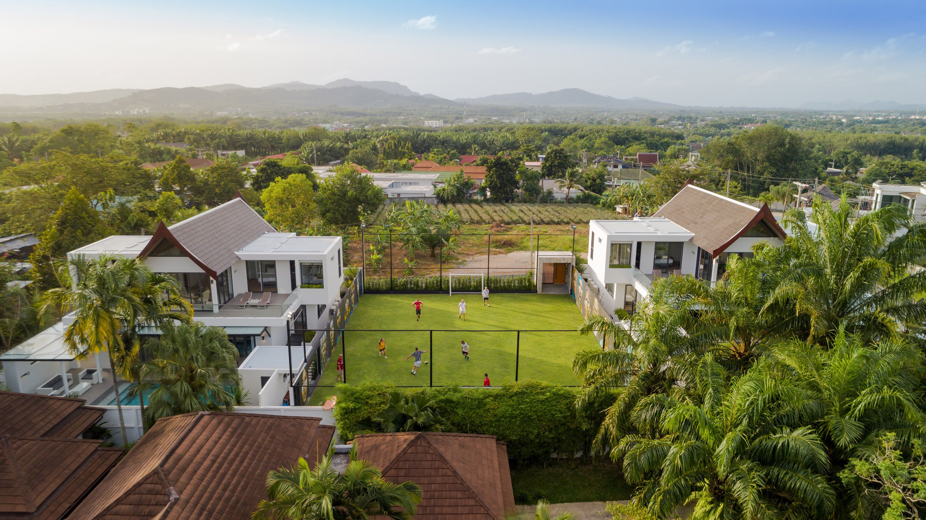 A residential area with modern houses, a well-maintained lawn, and a soccer field.