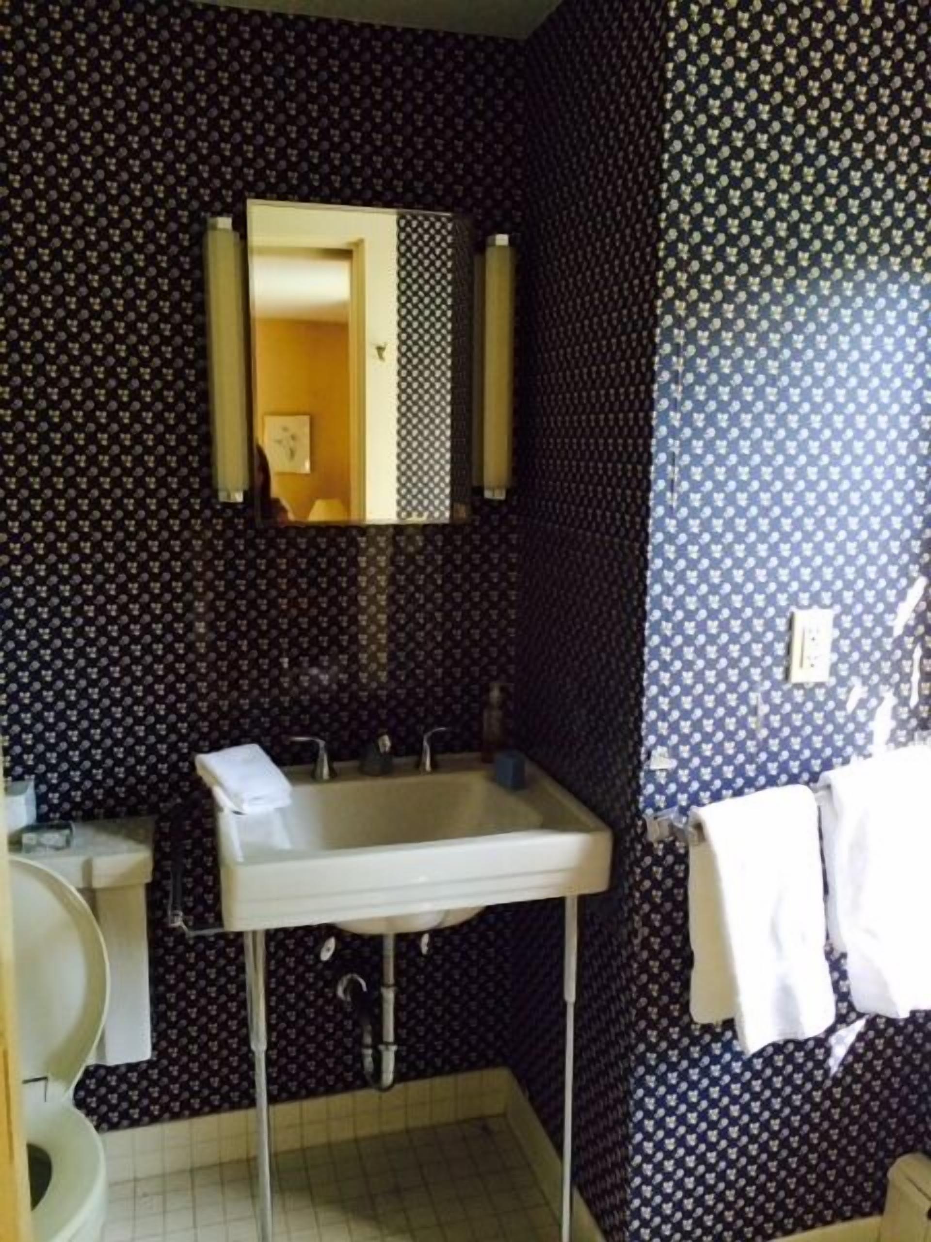 Un baño con lavamanos, espejo y perchero para toallas.
