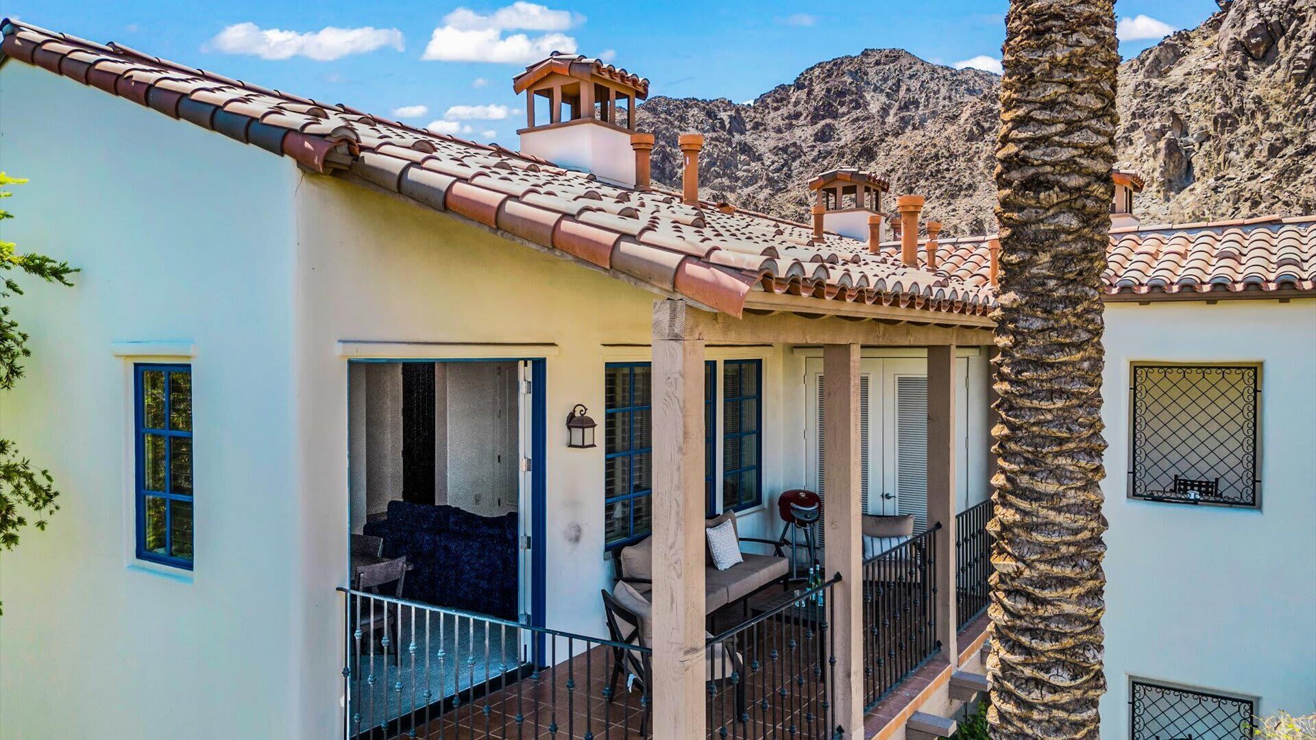 Un edificio de dos pisos con balcón, escalera y vistas a montañas rocosas.