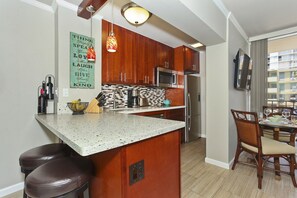 Una cocina moderna con armarios de madera, encimera de granito y una isla integrada con taburetes de bar.