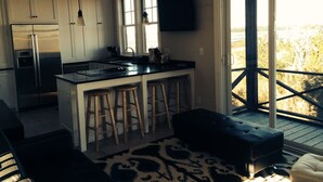 A modern kitchen with a large island, bar stools, and a sliding glass door leading to an outdoor deck.