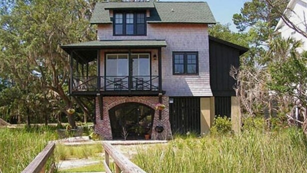 A two-story house with a balcony, a wooden deck, and a stone archway.