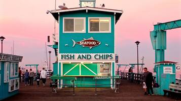 Un edificio turquesa con un letrero que indica 'SEAFOOD' y 'FISH AND CHIPS' sobre un muelle.