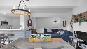 A modern living room with a dining table, sofa, and fireplace.